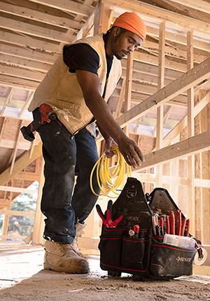 Electrician with wire in his hand reaching down into tool kit