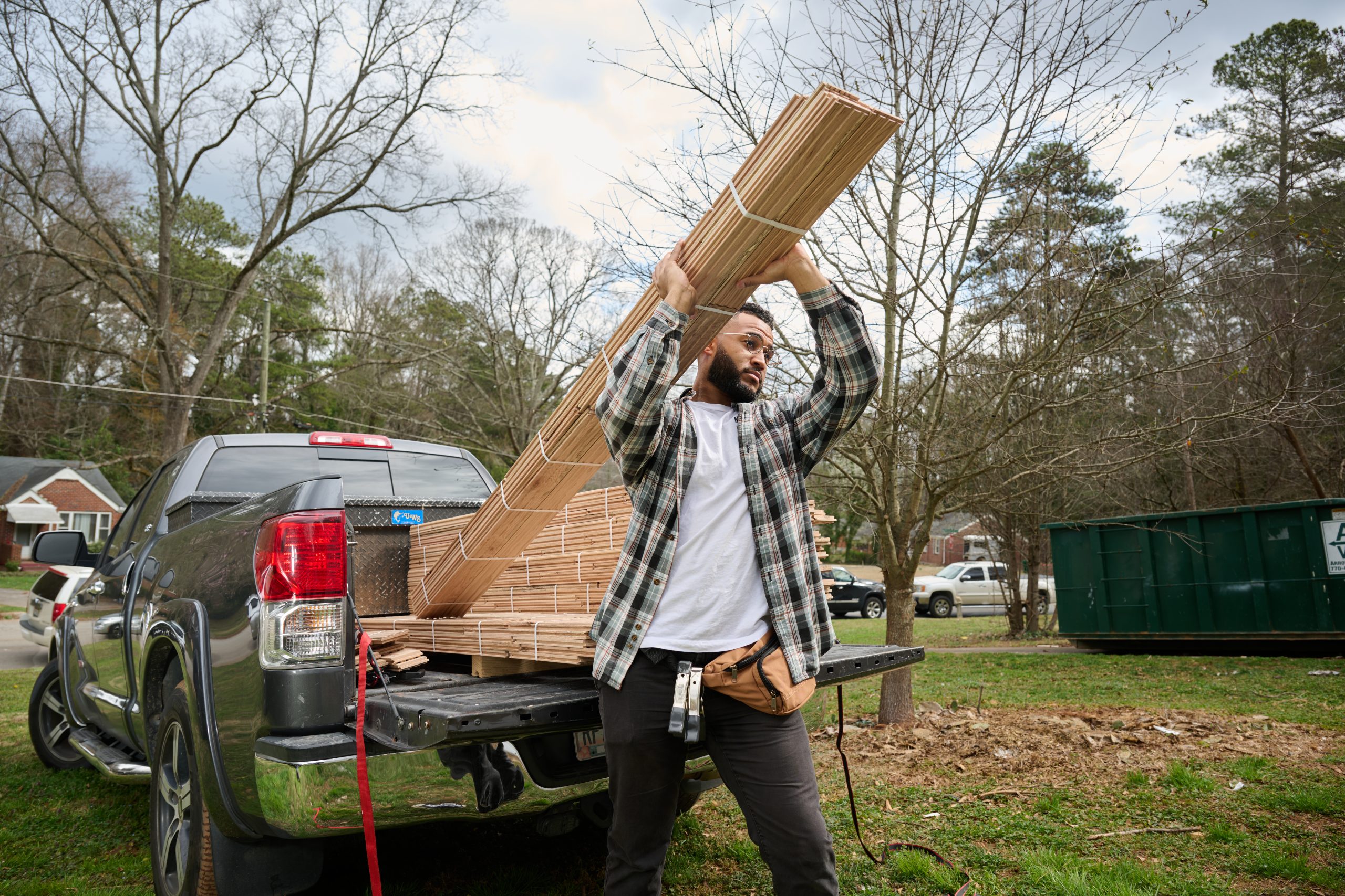 African American male unloading lumber from a work truck