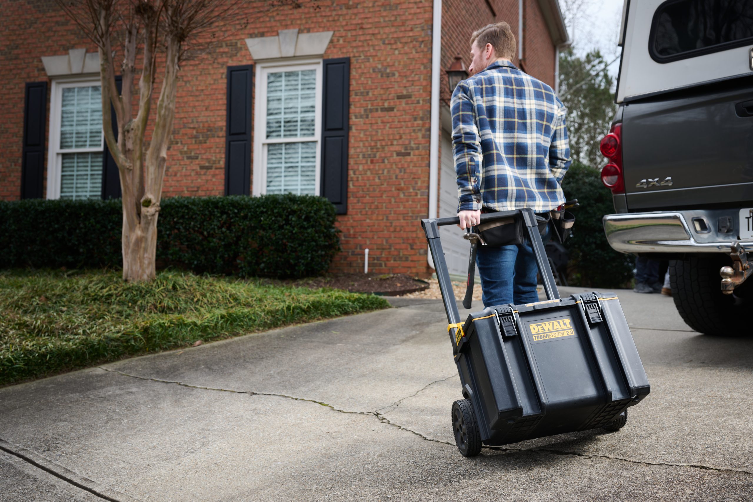 show-availability_card Caucasian male rolling tool kit from work truck up to a house